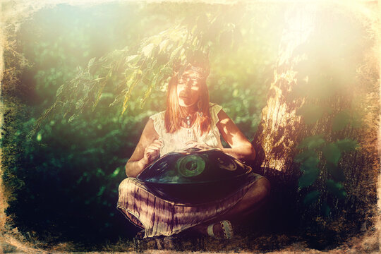 beautiful woman playing with hangdrum in nature. Old photo effect.