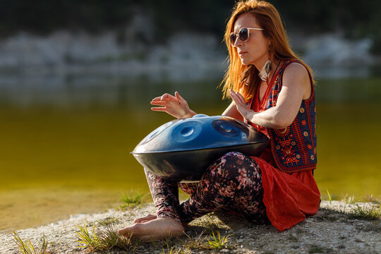 beautiful woman playing with hangdrum in nature.