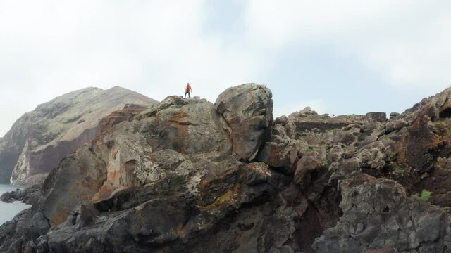 4K Man running onto steep rocky cliff and stopping looking around. Sports concept, travelling concept.