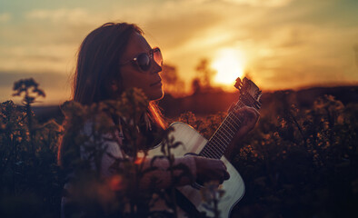 woman playing with guitar and blurred background.