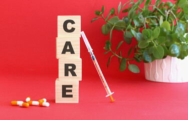 The word CARE is made of wooden cubes on a red background with medical drugs. Medical concept.