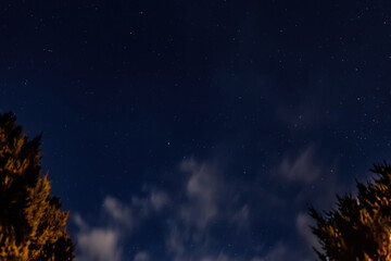 Fototapeta premium Blue night sky with stars and white moving clouds