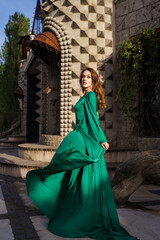 Naklejka premium beautiful young woman in long green dress standing posing against the backdrop of a fairytale castle