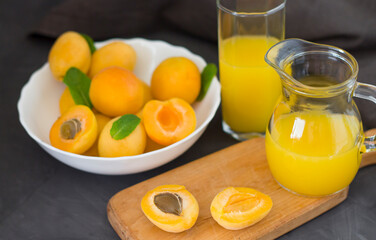 Apricots in a white plate and apricot juice. Apricots on a wooden board. Dark background. copyspace
