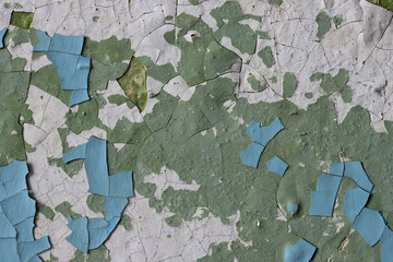 Peeling paint on the wall. Old concrete wall with cracked flaking paint. Weathered rough painted surface with patterns of cracks and peeling. Grunge texture for background and design. High resolution.