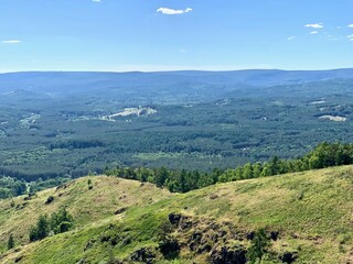 Awesome panoramic view. Blue mountains and sky, green hills. A sign on the side of a mountain