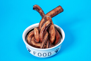 Ceramic bowl with heap of tasty dried snacks pet  food on blue background. Healthy nutrition