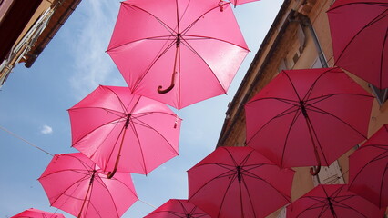 Elements of architecture of Grasse with pink umbrellas between houses, France