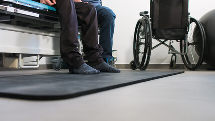 Obraz premium Physiotherapist exercising with disabled person using wheelchair on a therapy table.