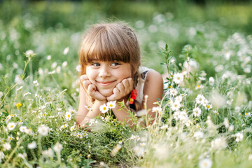 Pretty girl lying in daisy field and smiling to camera, unity with nature, childhood