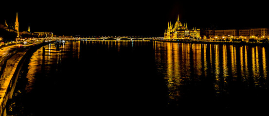 Fototapeta na wymiar A panorama view of the illuminated shores of the River Danube in Budapest at night in the summertime