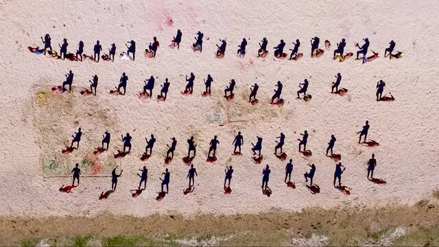 Aerial view of a large group of young people dancing on the beach. Black Sea Coast. Sports activities on the beach. Flash mob. Shadow dance
