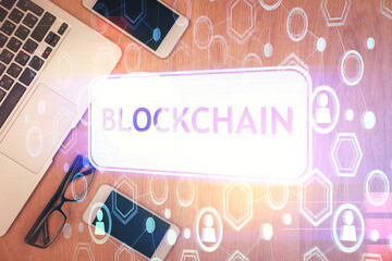 Double exposure of blockchain theme hologram over table with phone. Top view. Crypto technology...