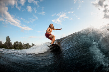 sportive young man wakesurfing down the river waves