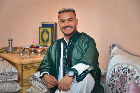 handsome Moroccan man (Arabic man ) (Muslim man ) wearing traditional cloths ( traditional outfit) and sitting next to the holy book in ramadan 
