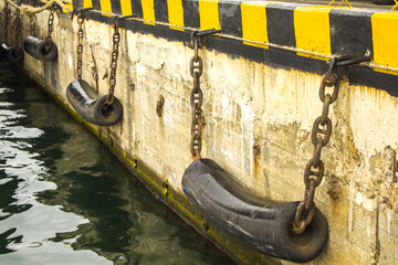 The small pier with bollards and fenders on a summer day