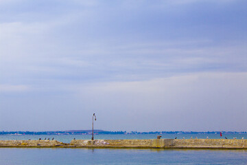 Dilapidated old fishing dock collapsing into the sea. Walking paths on the promenade. 