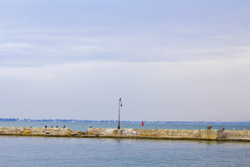Dilapidated old fishing dock collapsing into the sea. Walking paths on the promenade. 
