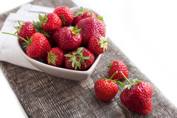 Breakfast with strawberries on wooden desk. Breakfast for child. Strawberries in a white heart-shaped bowl