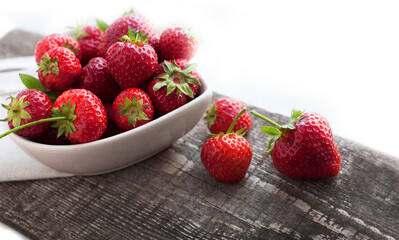 Breakfast with strawberries on wooden desk. Breakfast for child. Strawberries in a white heart-shaped bowl