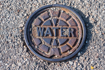 Rusty cover for water utility access on city street