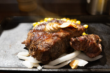 grilled steak serving with butter, onion, garlic on hot plate