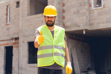 Worker at a construction site with thumbs up and self-confident