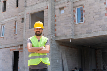 Construction worker looking at camera with hardhat in construction site background