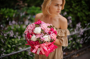 Bright pink bouquet of roses and other flowers in the hands of woman