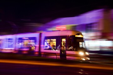 Naklejka na ściany i meble City ​​tram public transport. tram in motion with blurry background with purple and pink lights. Eskisehir/Turkey