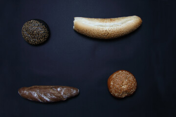 two baguettes and two scones isolated on black background flat lay