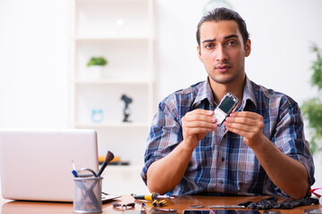 Young male technician repairing mobile phone