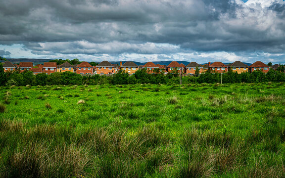 Row of brick houses seen across the green field in Lanarkshire, Scotland
