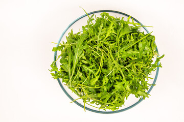 Green arugula leaves in a glass bowl. Top view. Healthy eating concept