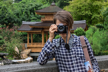 Woman tourist and photographer taking photo with digital camera in park, China