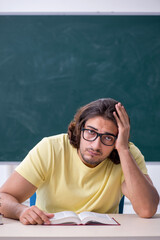 Young male geography teacher in front of blackboard