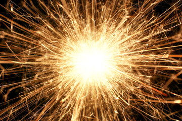 Close up of burning sparkler firework with lots of hot glowing embers exploding. For New Years or 4th of July celebration.