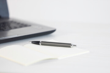 A pen on table desk with laptop and notepad with empty space background for design. Selective focus image in business concept.
