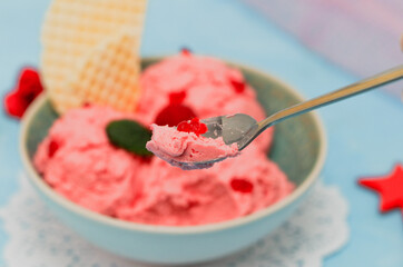 
raspberry ice cream on a dessert spoon close-up.