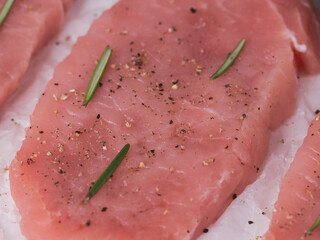 raw steak with rosemary on white crumpled parchment paper, top view close up.