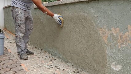 Medium shot of handyman smoothing the texture on a repaired stucco wall   