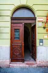 Naklejka premium Elegant brown wooden door in a building with green walls, baroque style. Historical heritage in the European city of Budapest, Hungary.