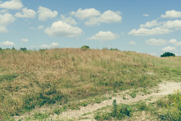 Fototapeta premium Clouds in the sky over a green hill in Texas Natural Park on a sunny June day.
