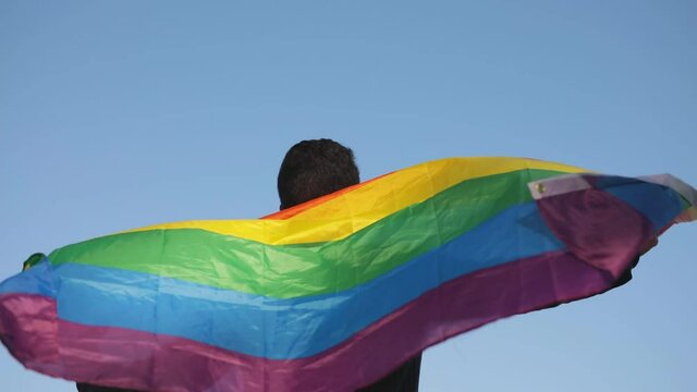 Young gay man smiling in the LGBT gay pride flag