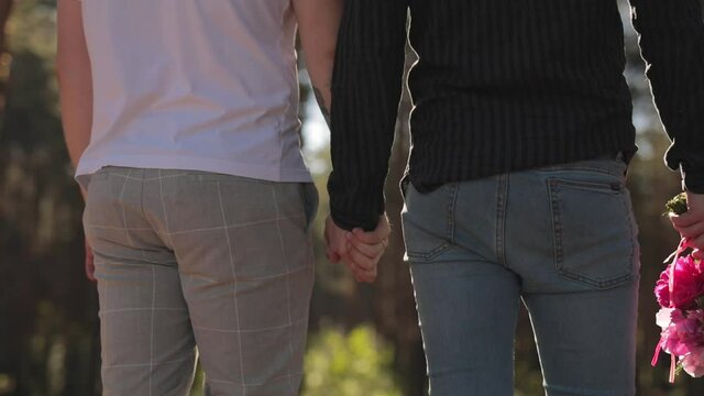 Close Up Of Two Male Hands Gently Touching And Holding Each Other. Cute Queer Relationship Concept. Gay Couple Are Casually Dressed. Park Outdoor