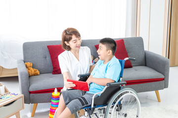 asian woman playing with disabled child on wheelchair via tablet in living room.
