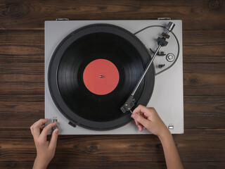 Hands on vinyl record players on a wooden background.