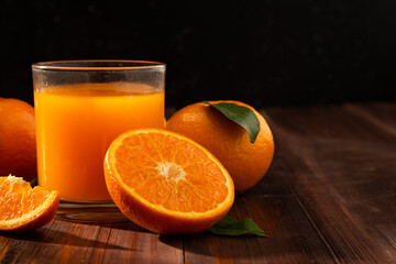Fresh orange juice in glass and oranges fruit on wooden table background with copy space.