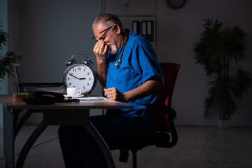Aged male doctor in the hospital at night