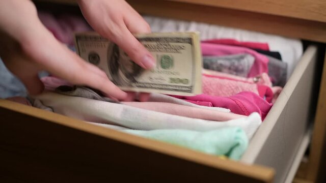 a woman hides money savings in children's things in a closet with clothes. Nest for difficult times